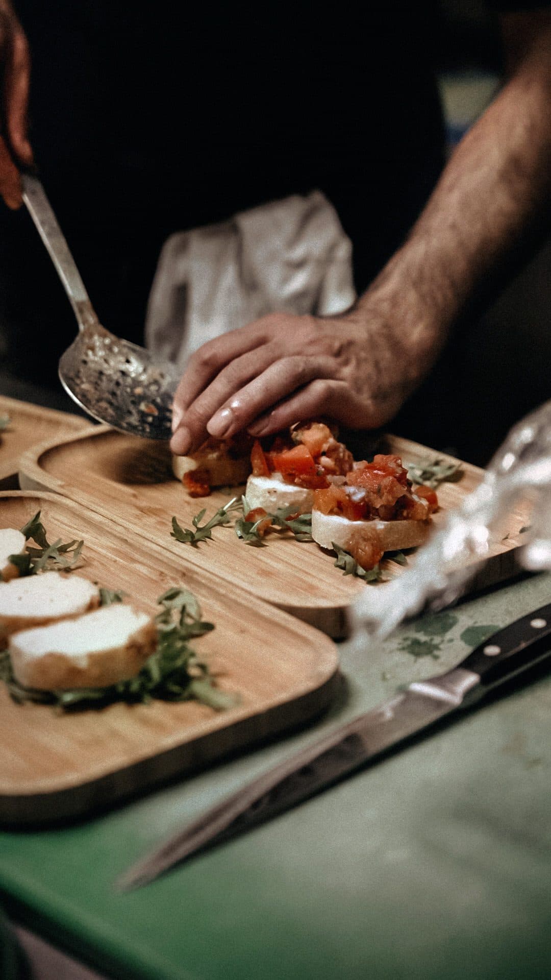 Hände richten Bruschetta mit Tomaten auf Holzbrettern an