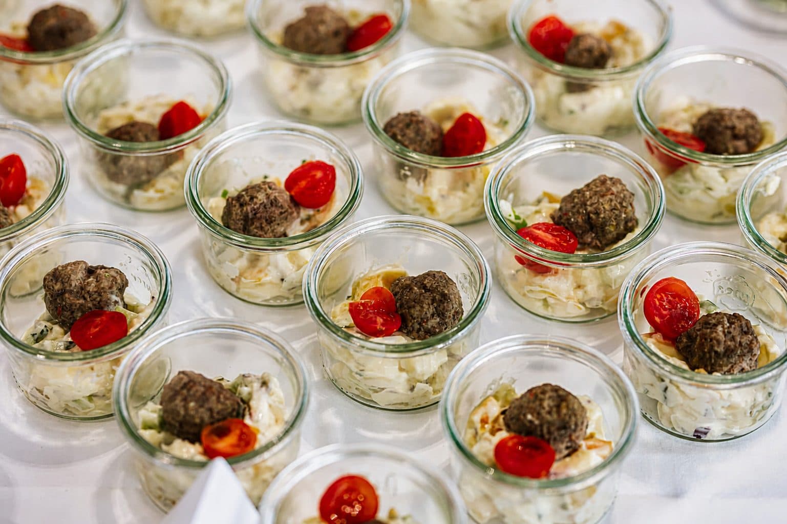 Vorspeisen im Weckglas mit Hackbällchen und Tomate, in Reihen auf der Buffettafel