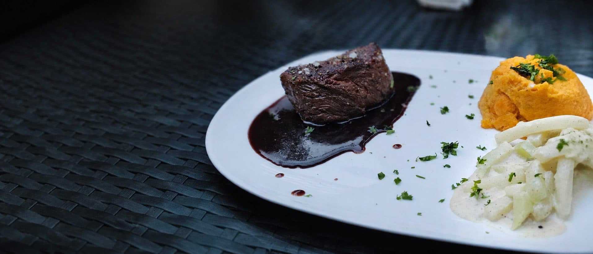Rinderfilet an Rotweinjus mit Süßkartoffelpüree und Kohlrabi auf weißem Teller