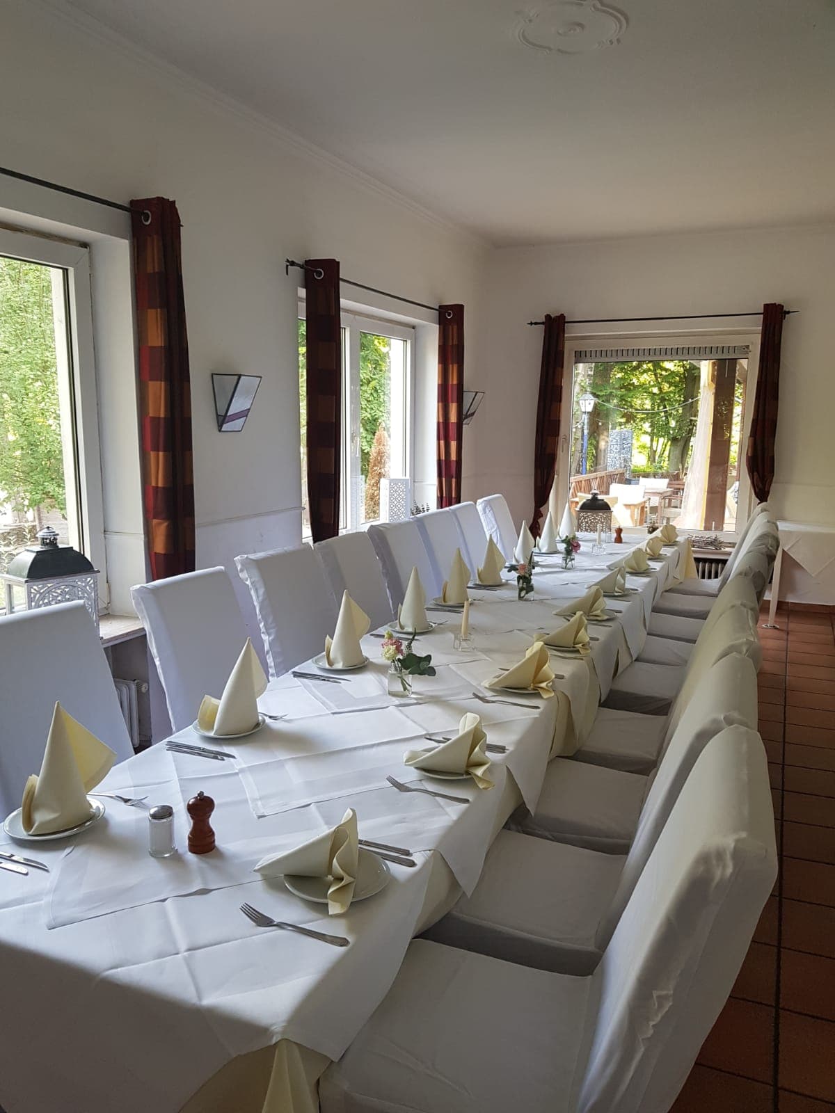 Kaminzimmer mit gedeckten Tischen und hohen Fenstern