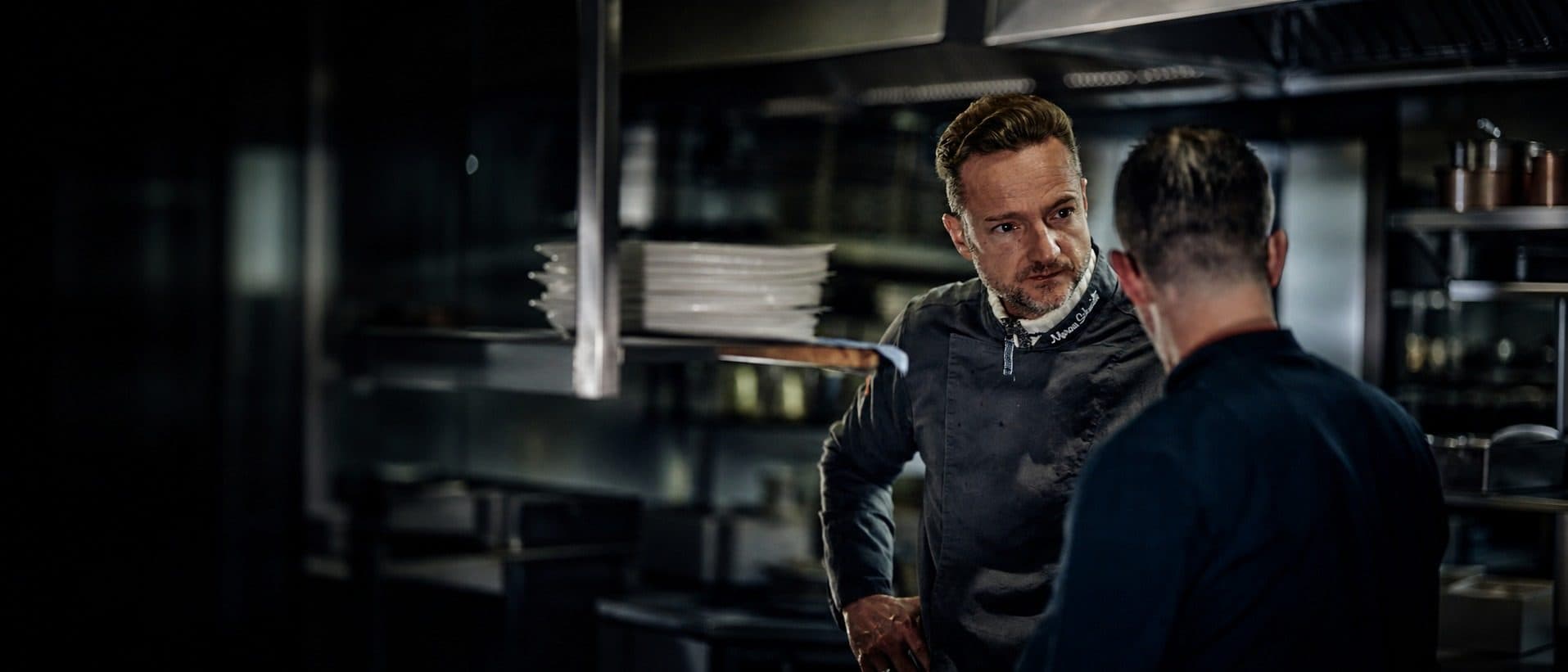 Küchenchef im Gespräch mit einem Kollegen in der Küche