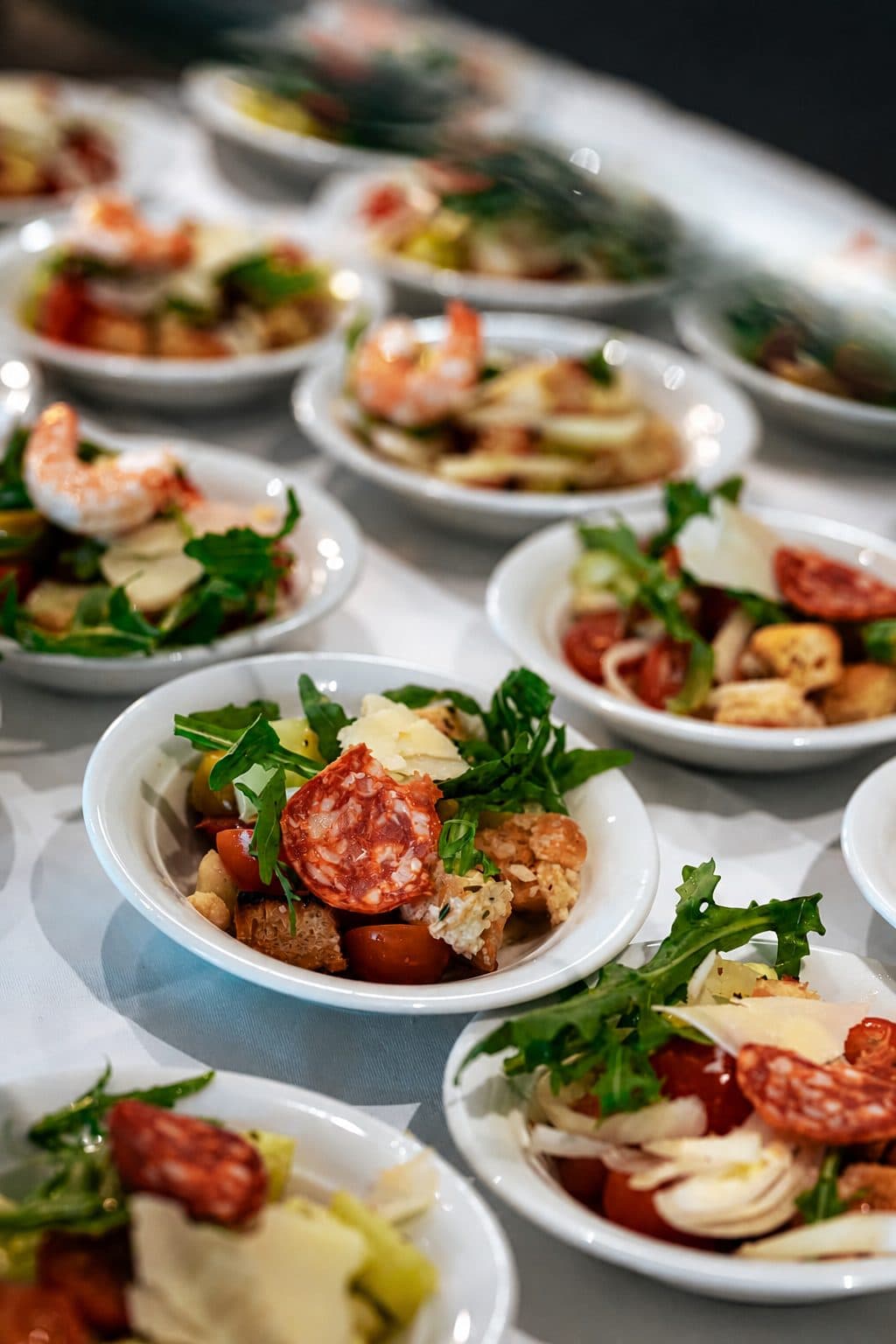 Kleine Vorspeisenteller mit Salat, Salami und Garnelen in Reihen auf dem Buffet