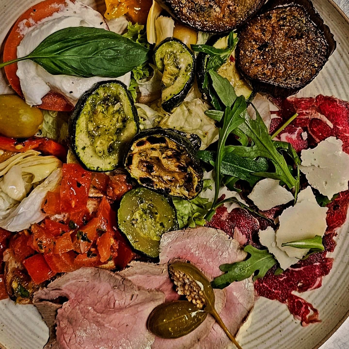Antipasti-Platte von oben: gegrilltes Gemüse, Aufschnitt und Parmesan