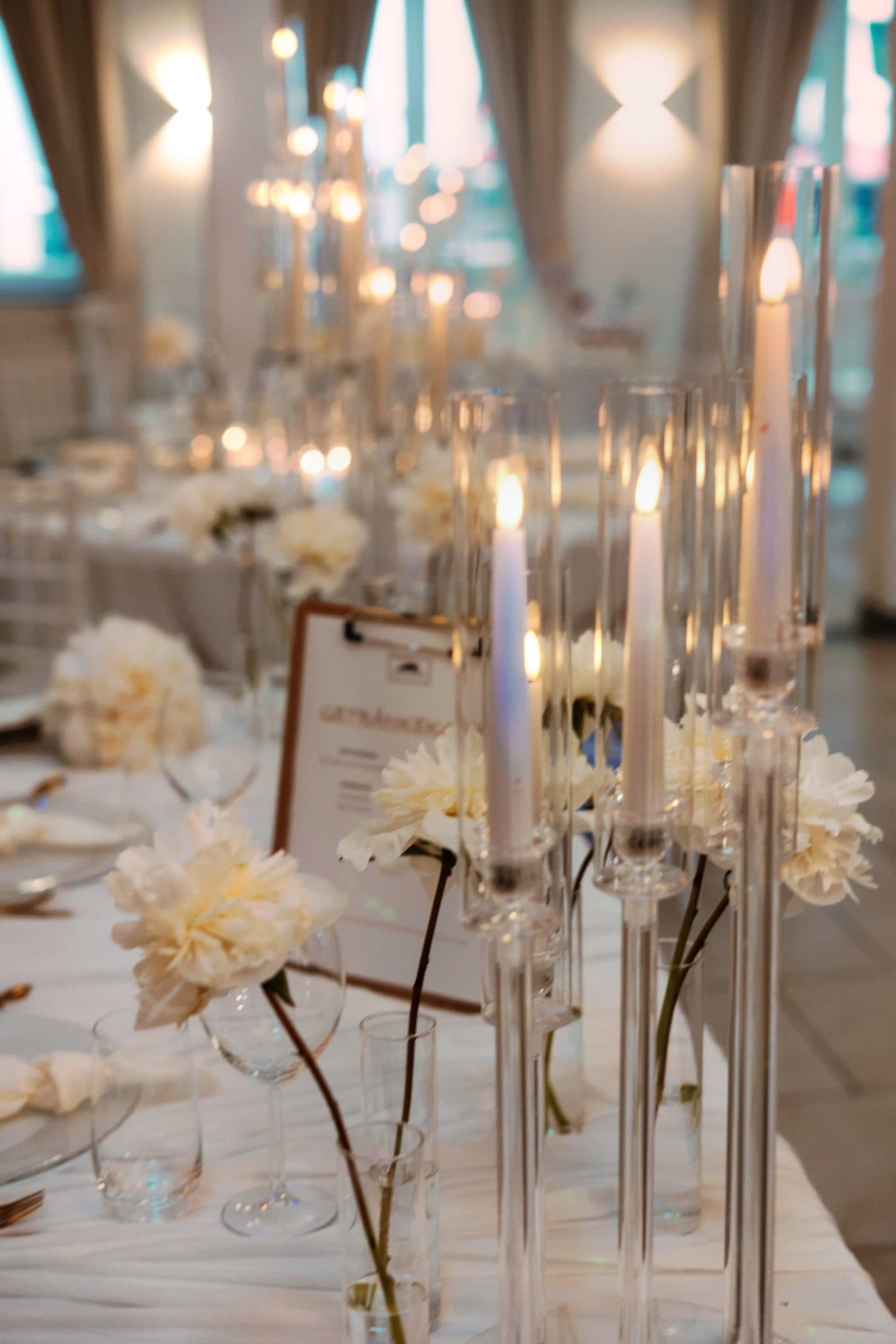 Kerzen und weiße Blumen auf der festlich gedeckten Hochzeitstafel