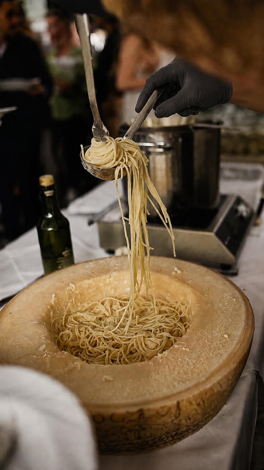 Pasta wird in einem ausgehöhlten Parmesanlaib geschwenkt und mit der Kelle angerichtet