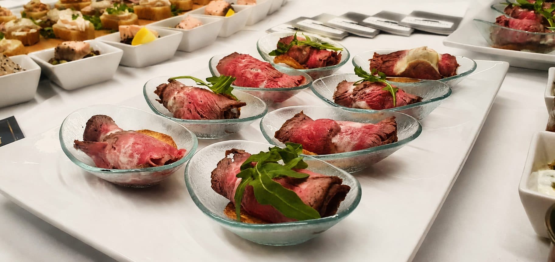Roastbeef-Röllchen mit Rucola in Glasschälchen auf dem Buffet