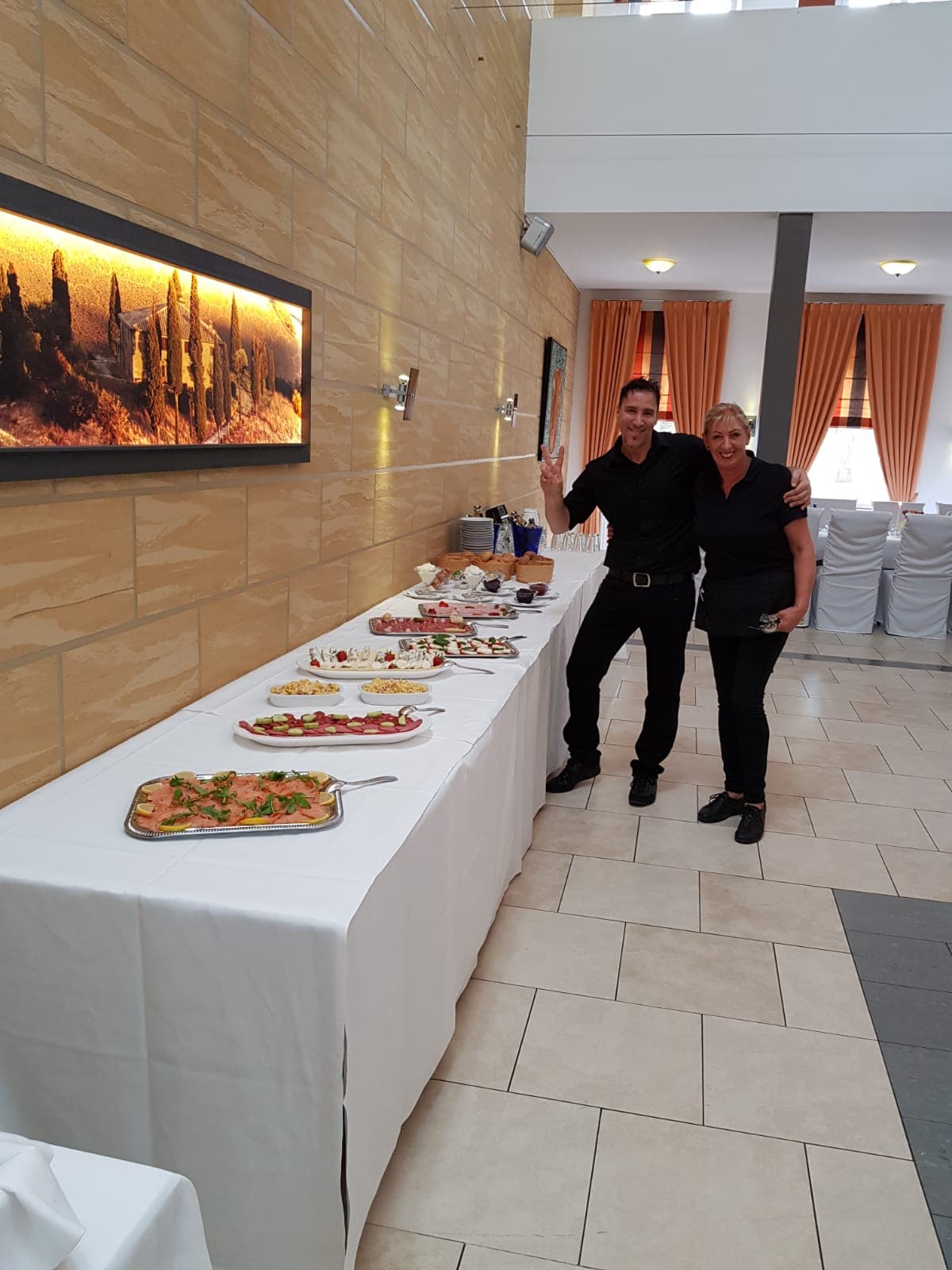 Zwei Mitarbeitende neben dem aufgebauten Buffet