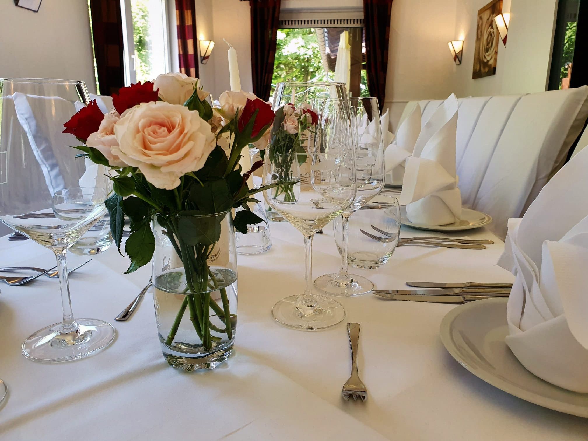 Rosenstrauß auf festlich eingedeckter Tafel mit Weingläsern